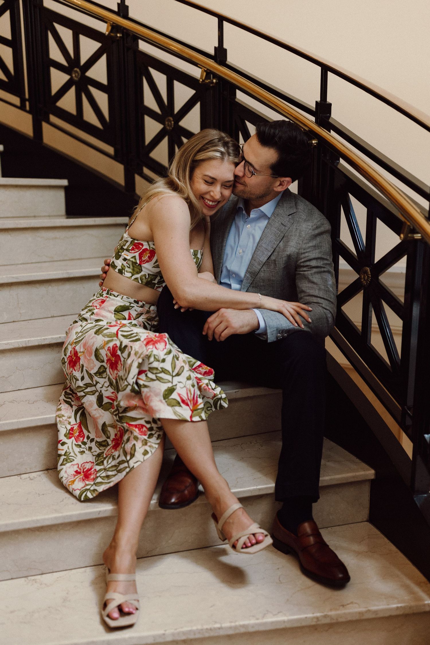 Intimate moment captured on elegant staircase with decorative railings.