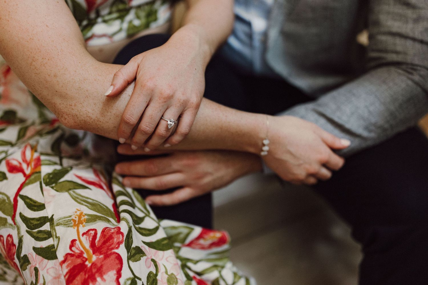 Close-up shot of hands resting on a floral dress during an intimate moment.