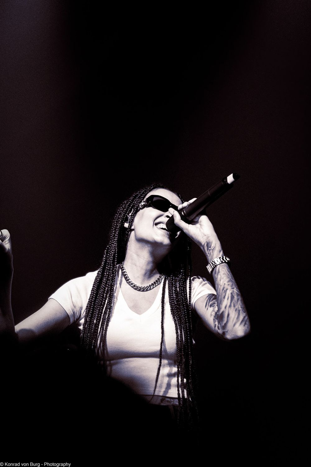Dramatic black and white performance shot with dramatic stage lighting and silhouette.