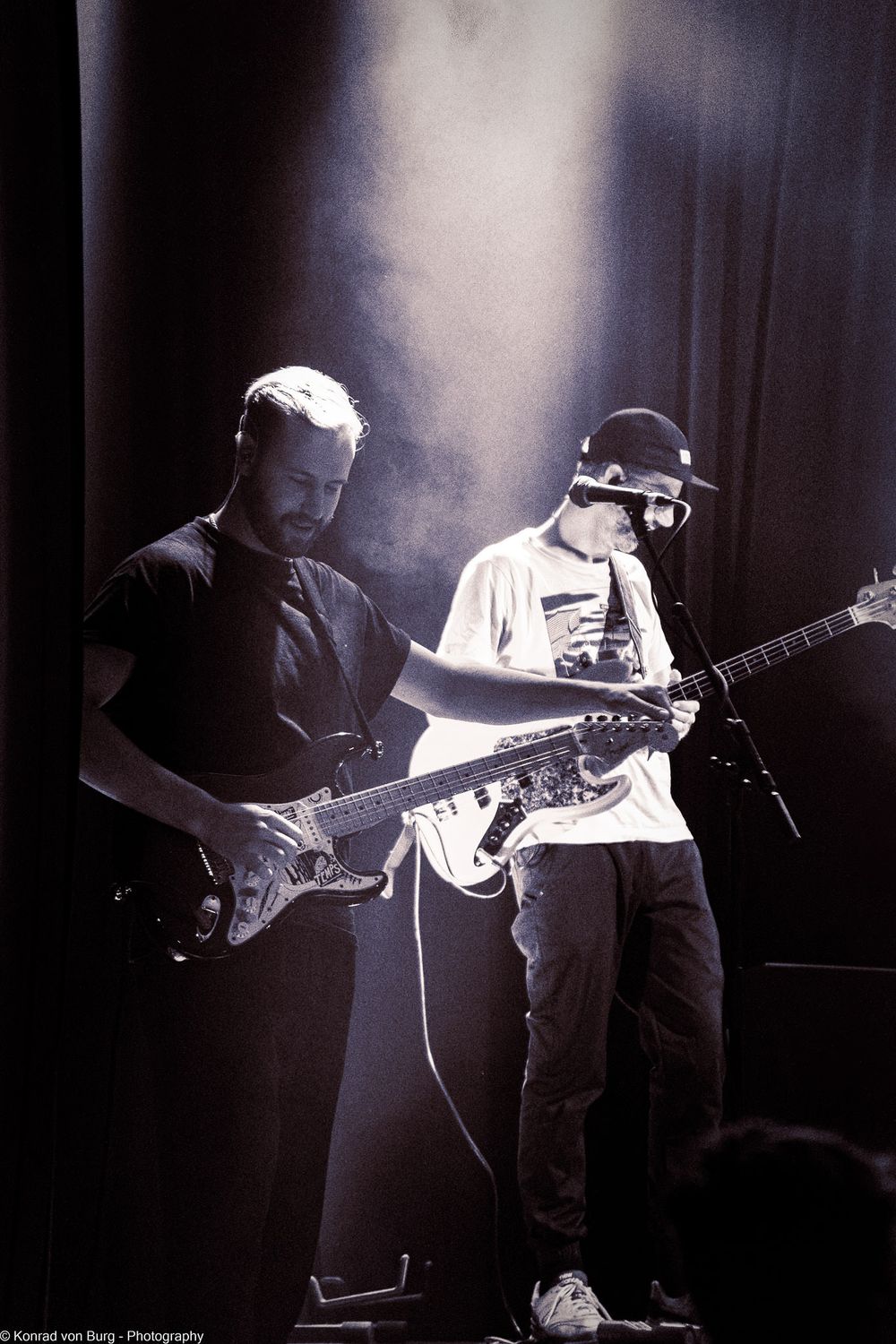 Musicians performing on stage in dramatic backlighting with guitar silhouettes.