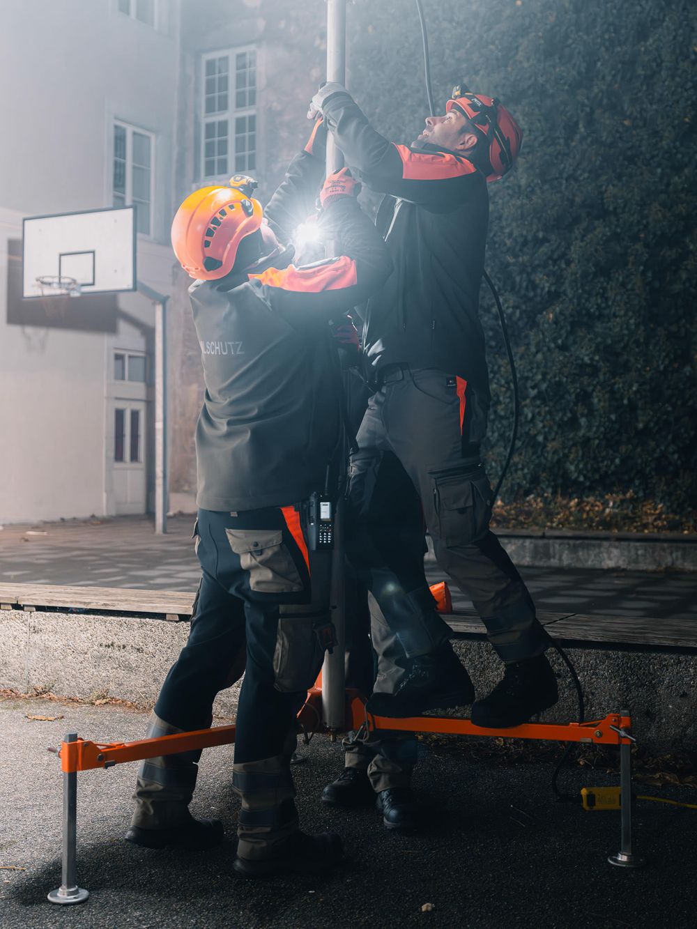Emergency responders in orange safety gear working together on equipment during training exercise.