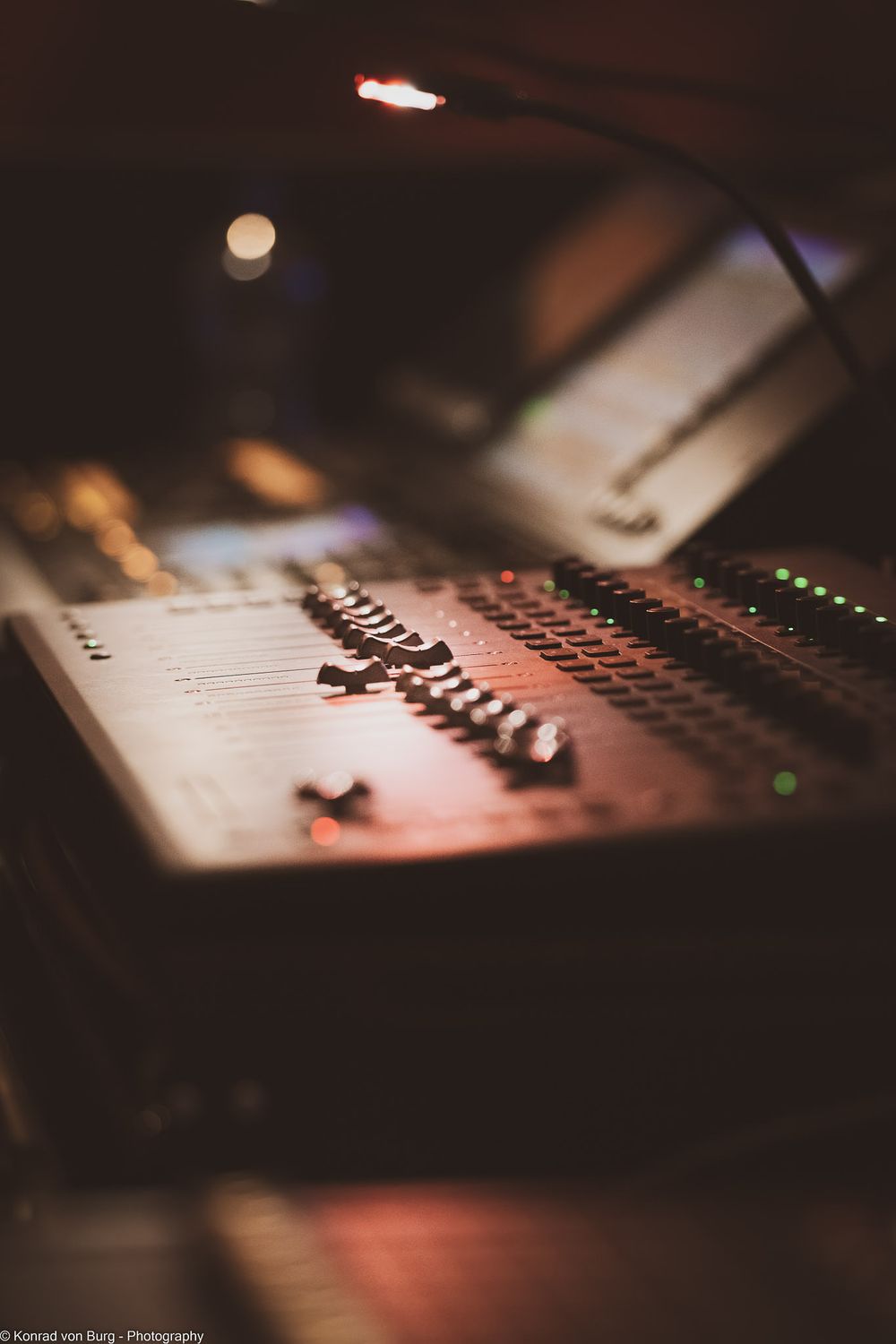 Audio mixing console faders and controls in dark lighting with shallow depth of field.
