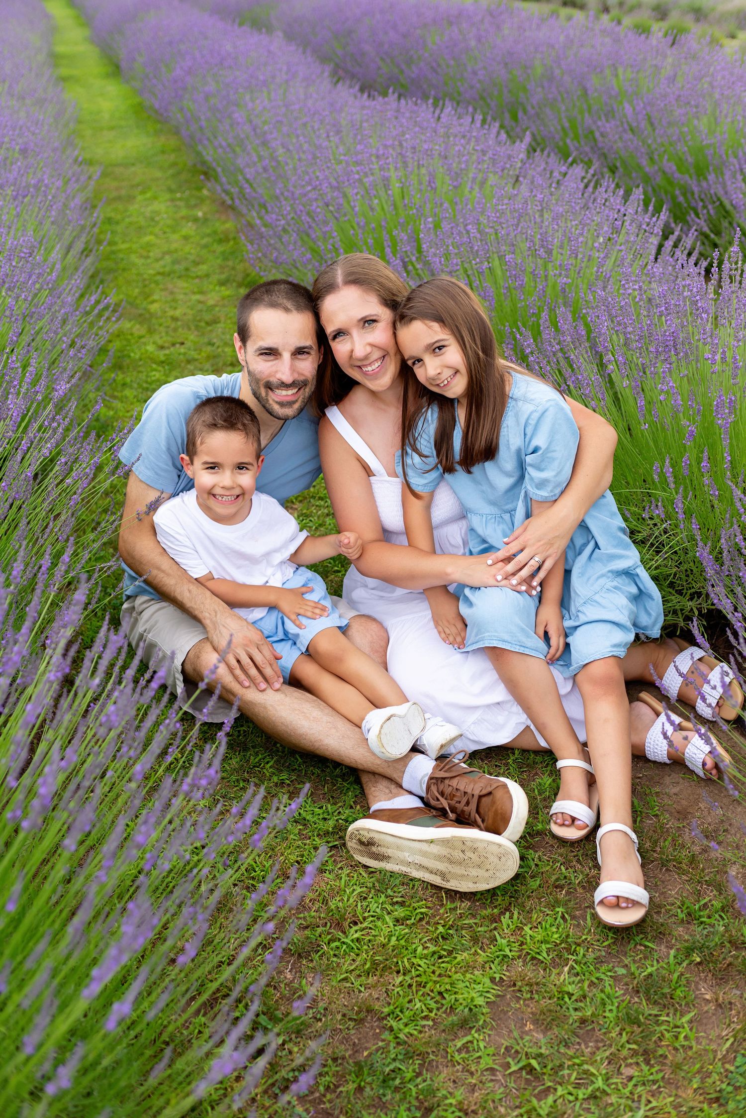 Family sitting together in a blooming purple lavender field on a sunny day at R&B Lavender.