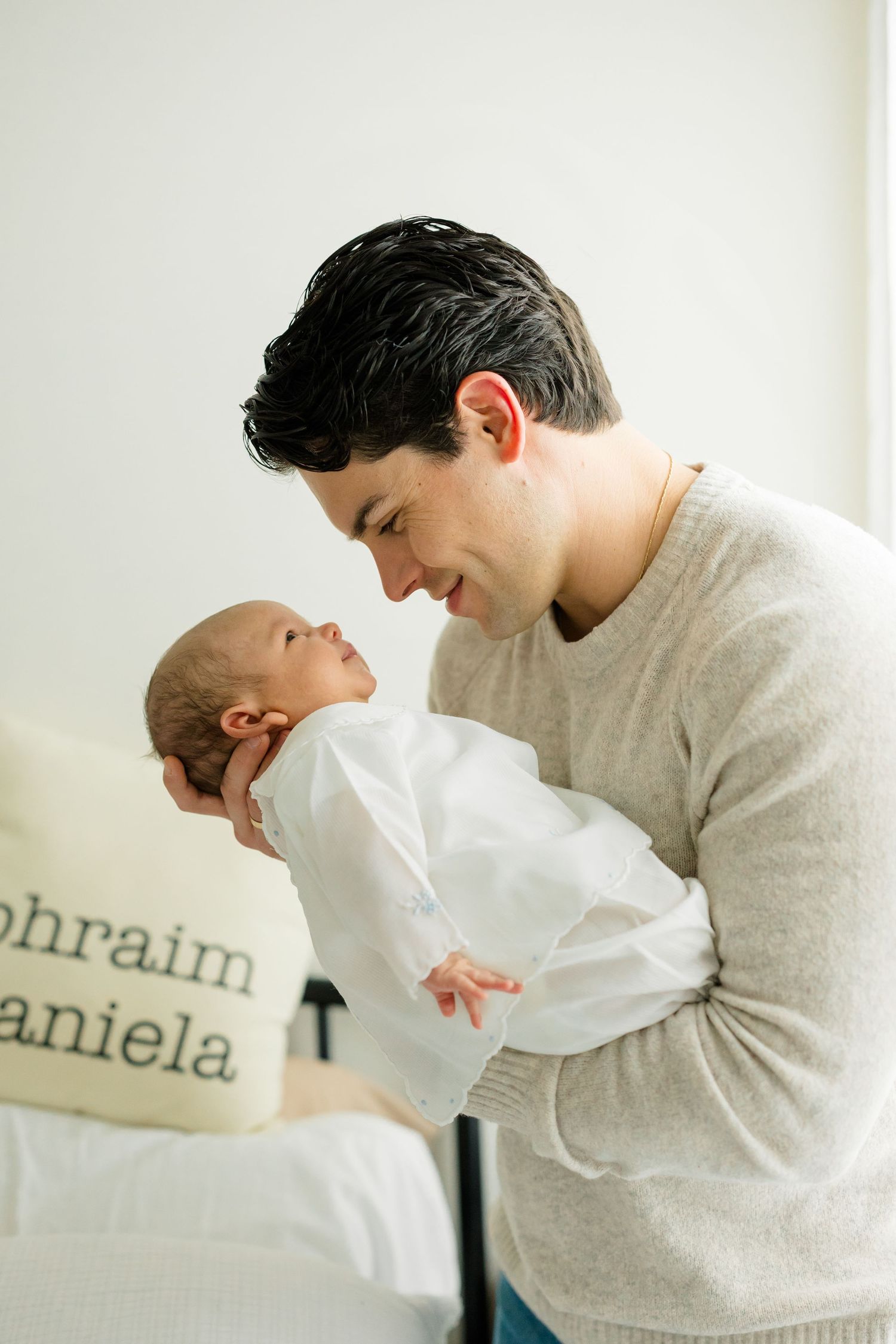 A tender moment captured in a series of four connected images showing a parent and baby interacting against a white wall.