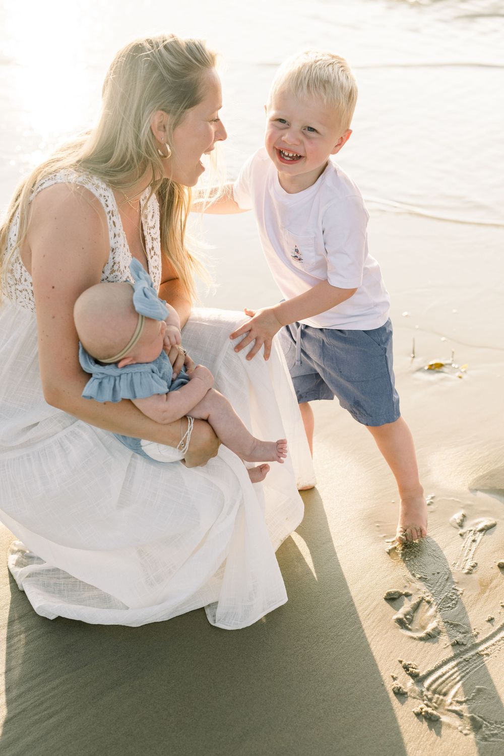 A heartwarming beach scene shows playful interactions between family members on the sand at sunset.