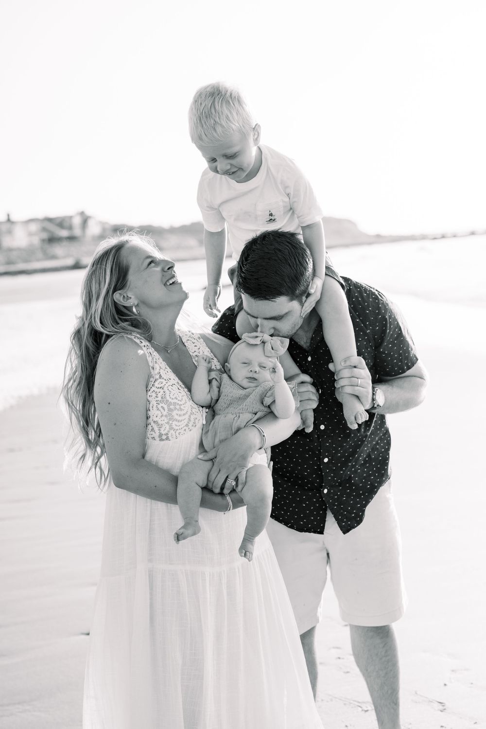 A joyful family moment captured in black and white on the beach during a casual photo session.