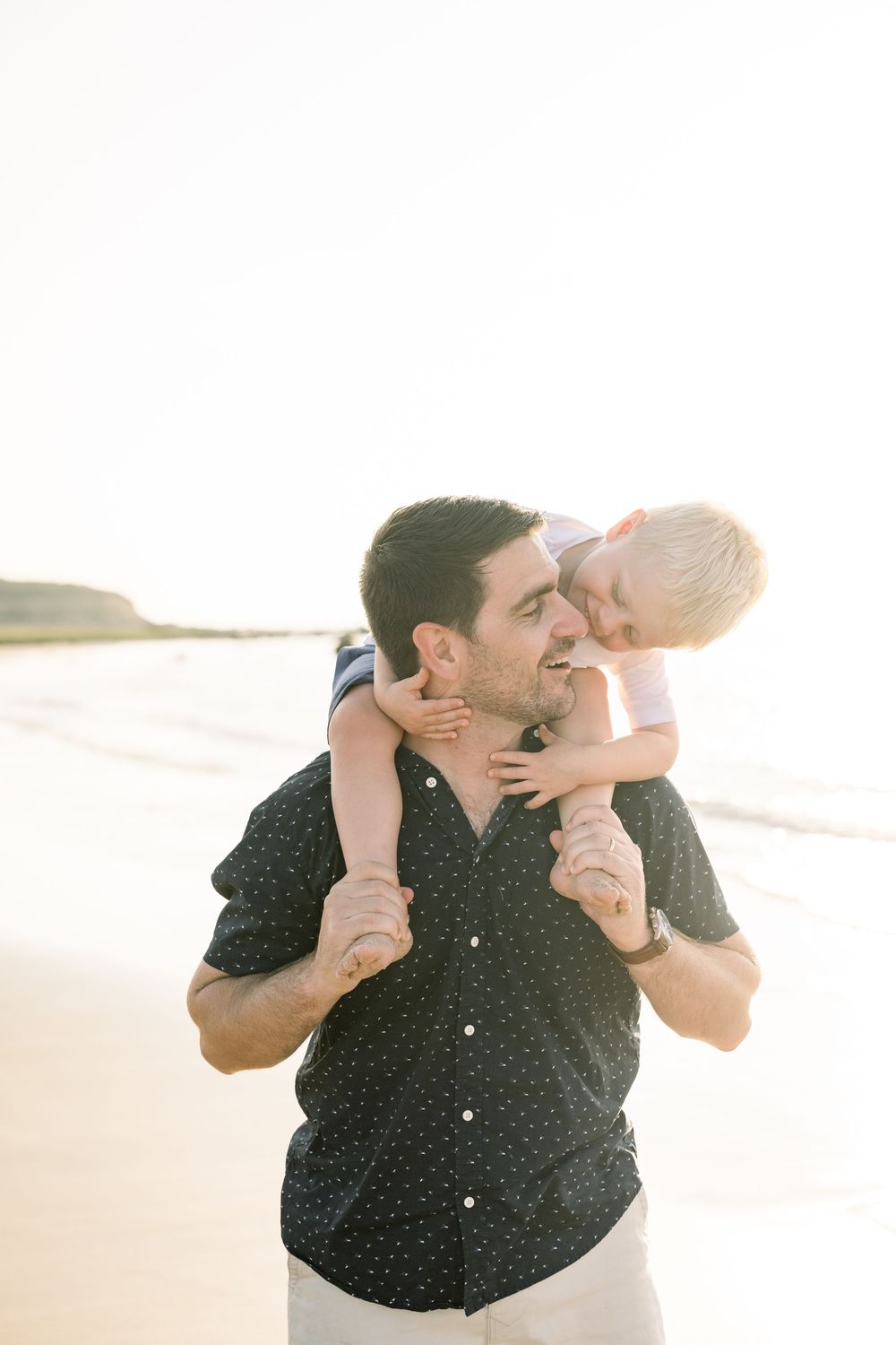 A couple shares a tender moment on a bright beach, embracing and laughing together in a series of candid photos.