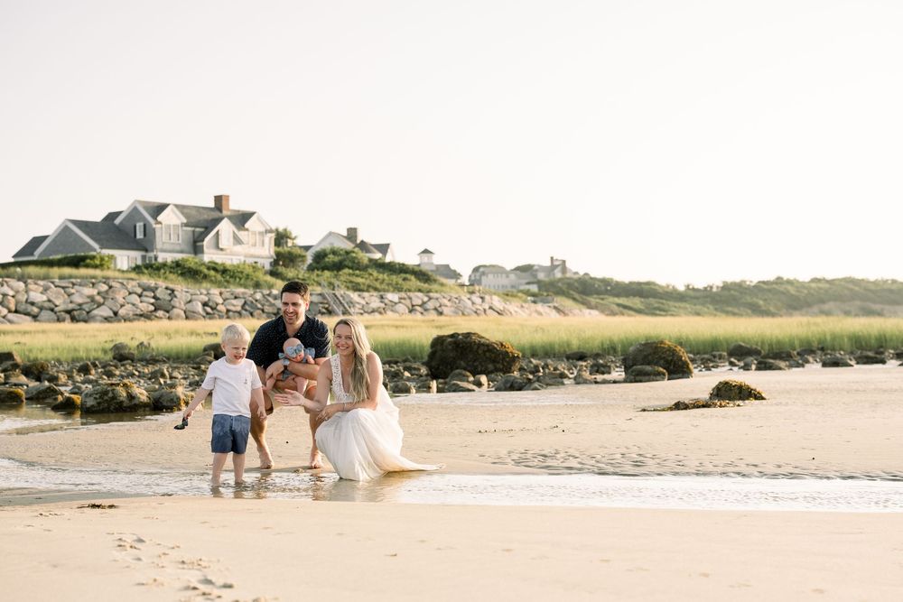 Family walking along a scenic beach path with rolling dunes and coastal vegetation in the background.