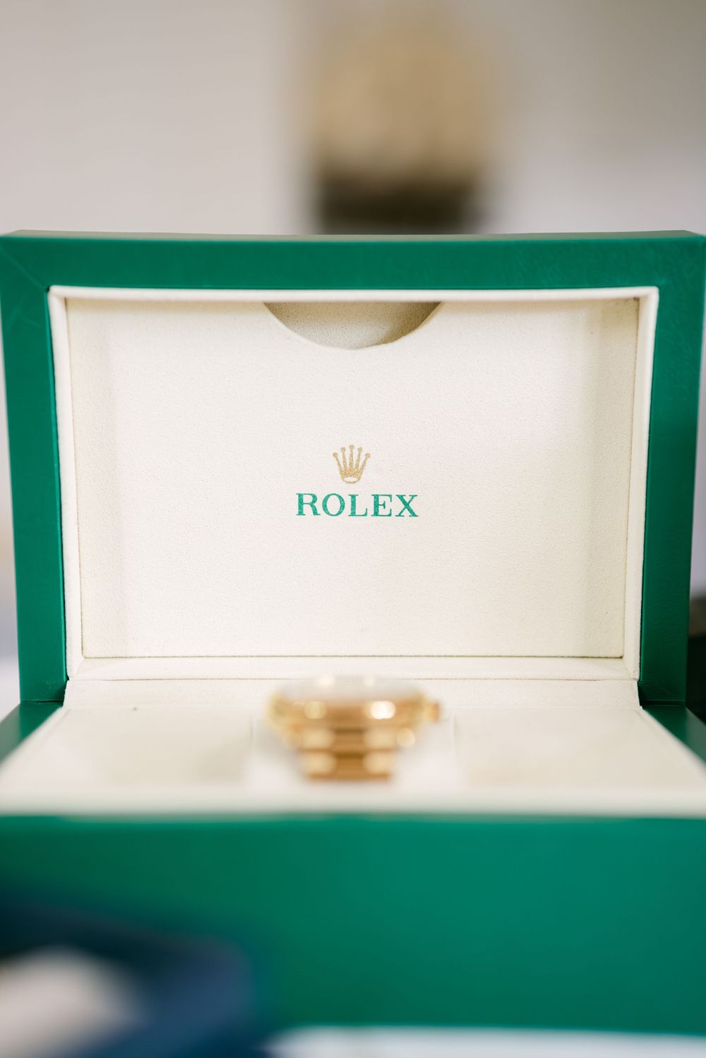 Close-up detail of a green Rolex watch box with the iconic crown logo visible on white background.