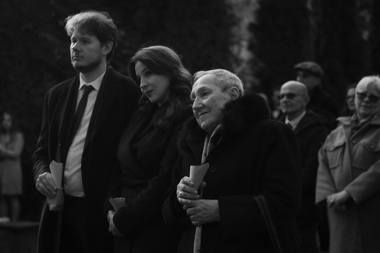 A black and white photograph shows a crowd of men in suits and formal attire gathered outdoors.
