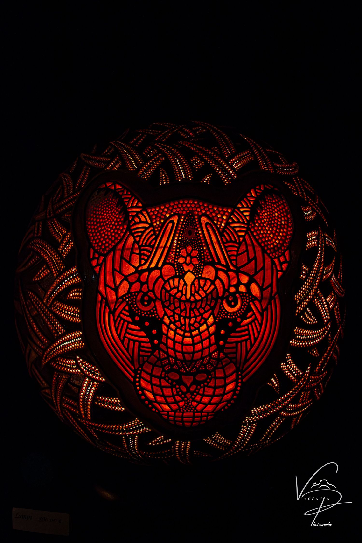 Ornate red gourd lamp with detailed geometric patterns glowing in the dark.