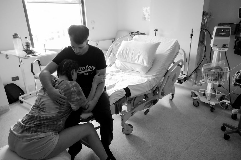 Medical room scenes showing tender interactions in black and white during a central coast birth session.