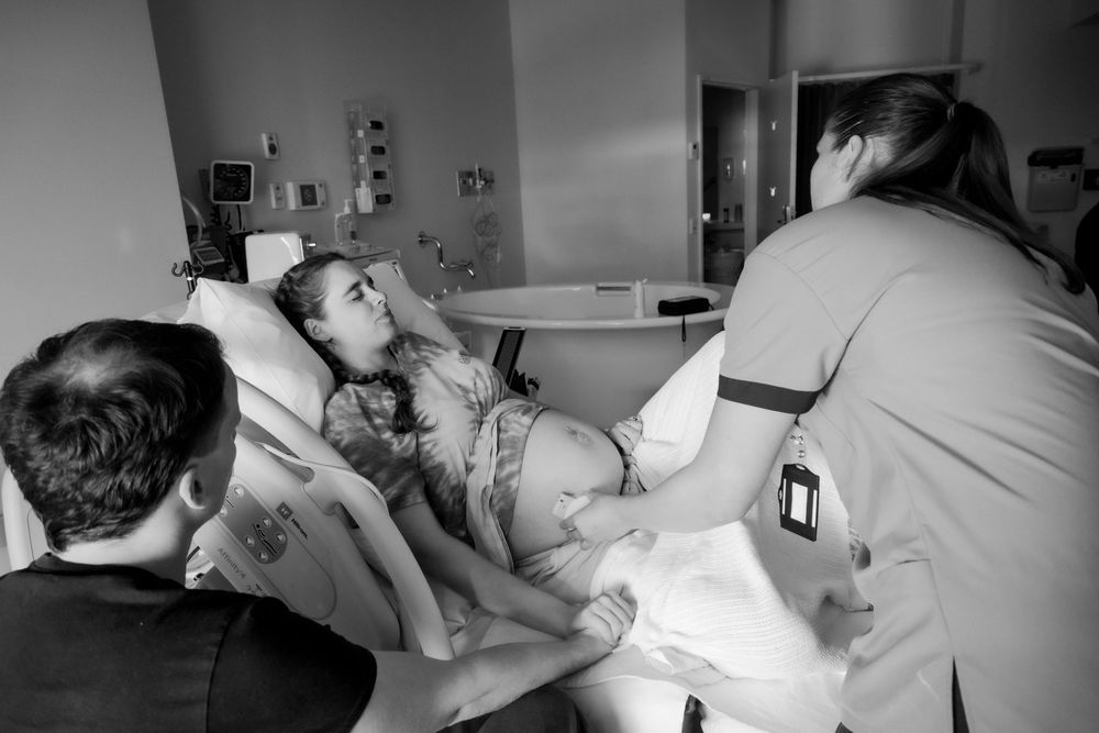 Medical professionals attend to a patient in a hospital delivery room during labor and birth during a central coast birth session.