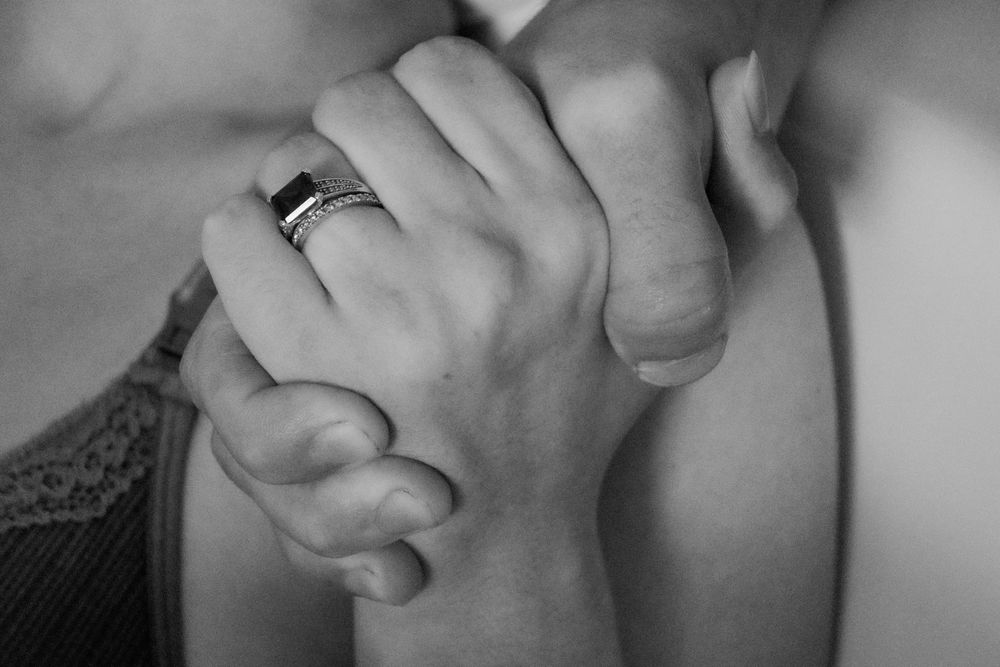 Intimate black and white photo showing hands clasped together in support during a central coast birth session.