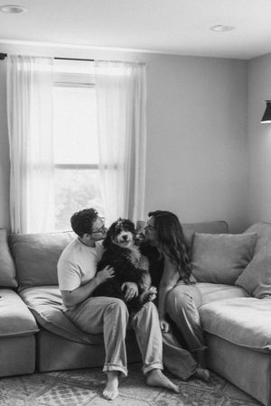 Two people share an intimate moment while lounging on a plush gray sofa.