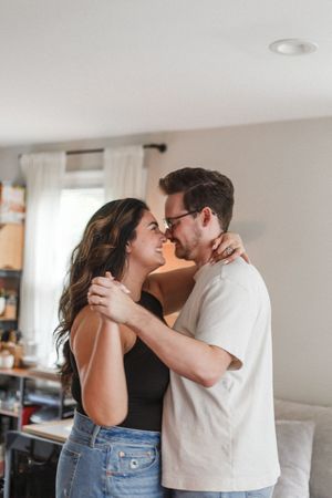 A romantic couple shares an intimate embrace in their sunlit living room.