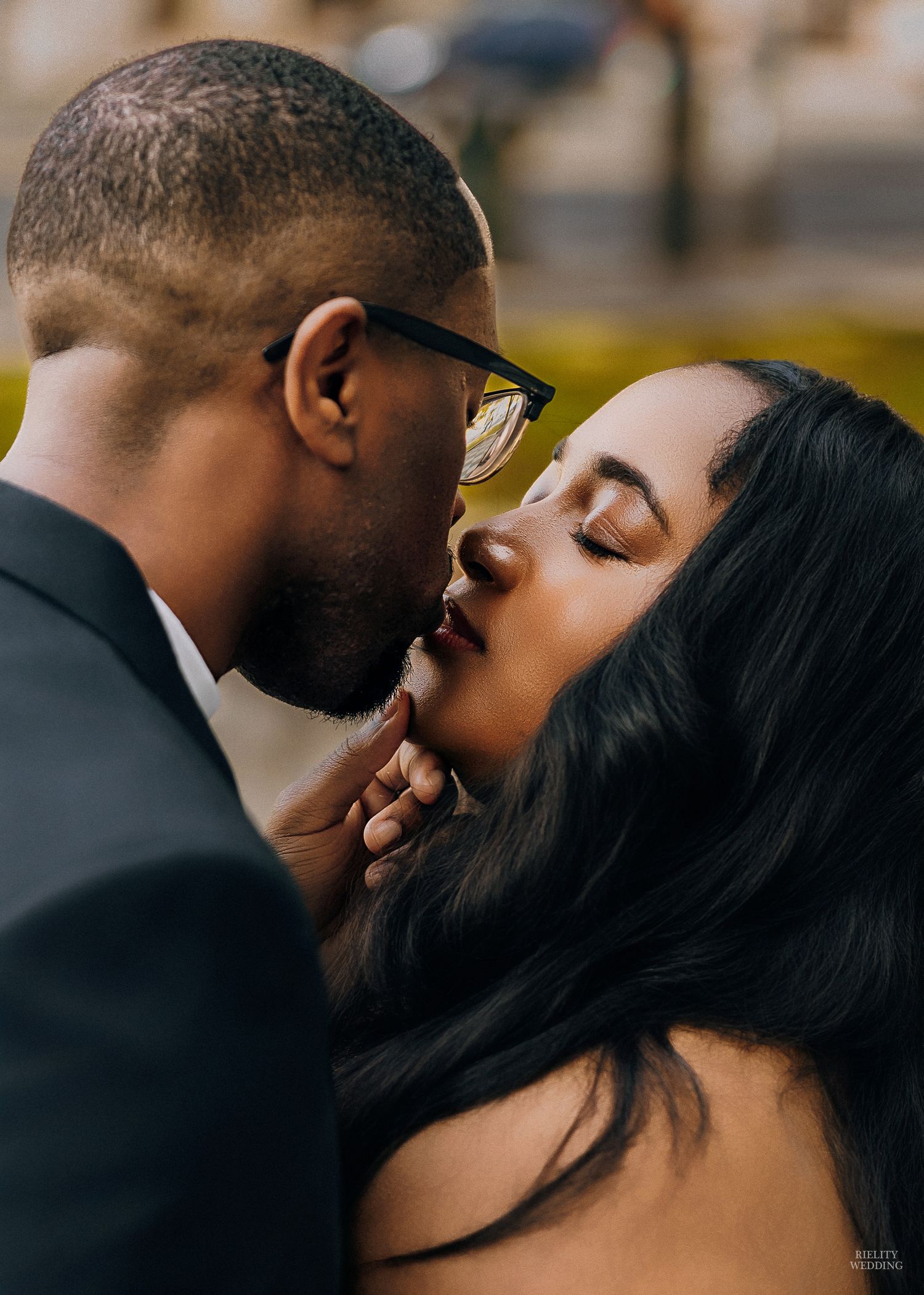 A romantic close-up portrait of a couple sharing an intimate kiss outdoors.