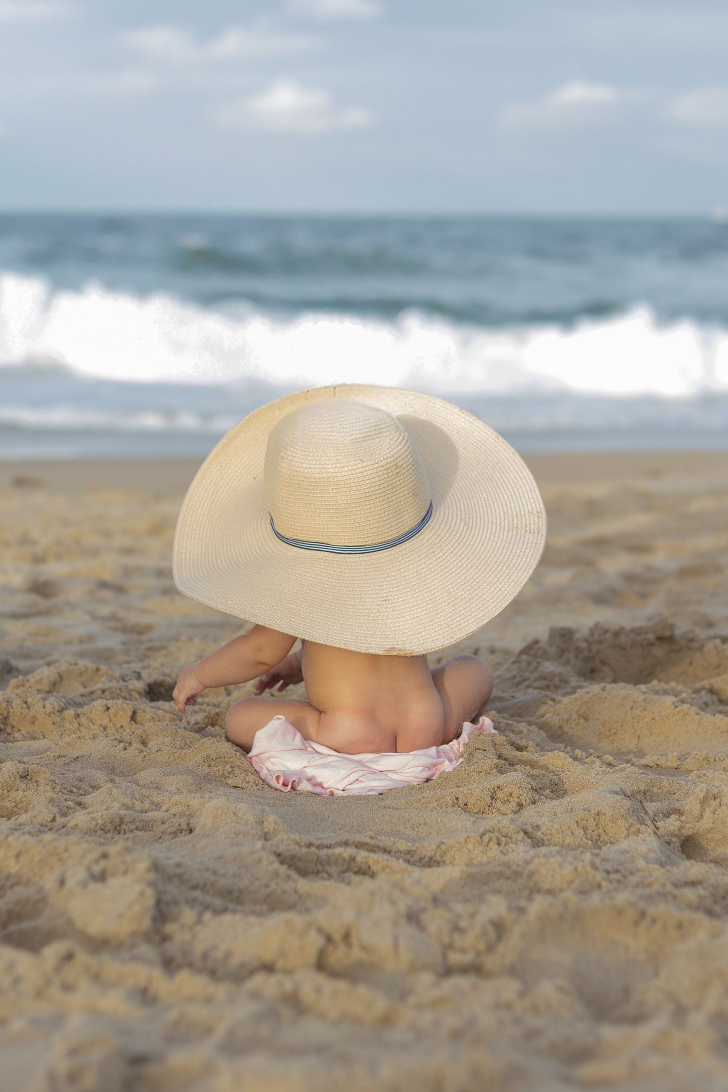 6 month girl session naked on the beach in a sun hat showing her butt cheeks