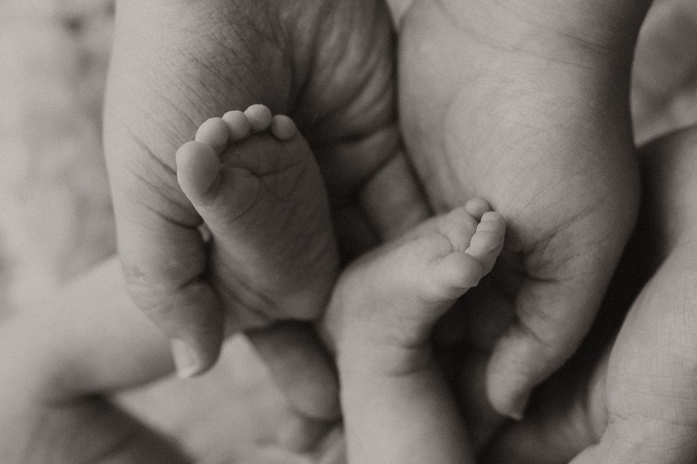 Close-up black and white photo of hands holding each other in a tender embrace.