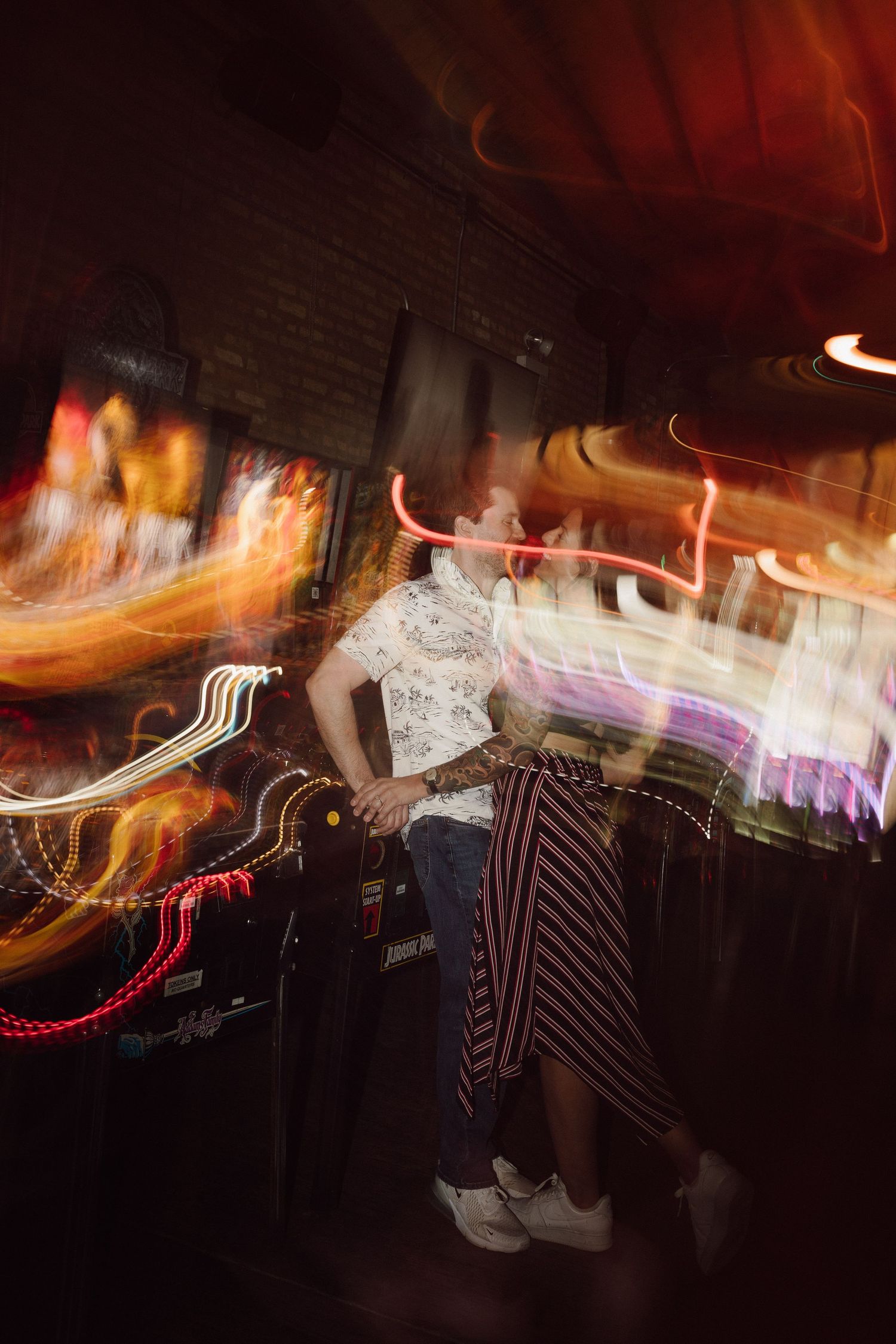 People leaning against arcade games socializing in Emporium Arcade with atmospheric lighting