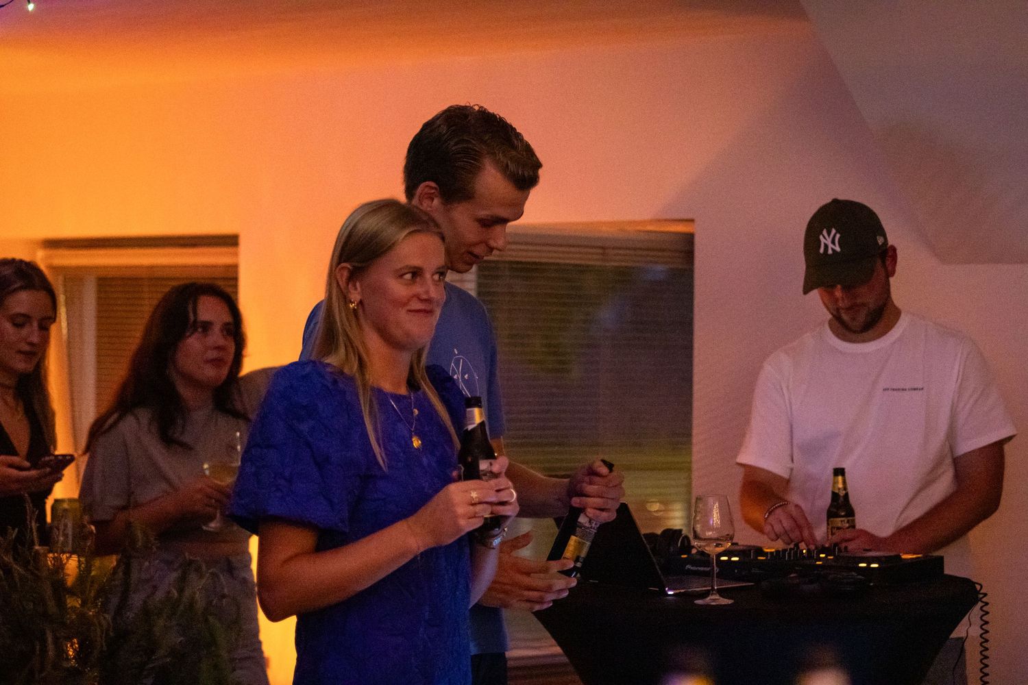 Sfeerbeeld van evenement met bezoekers en DJ op de achtergrond