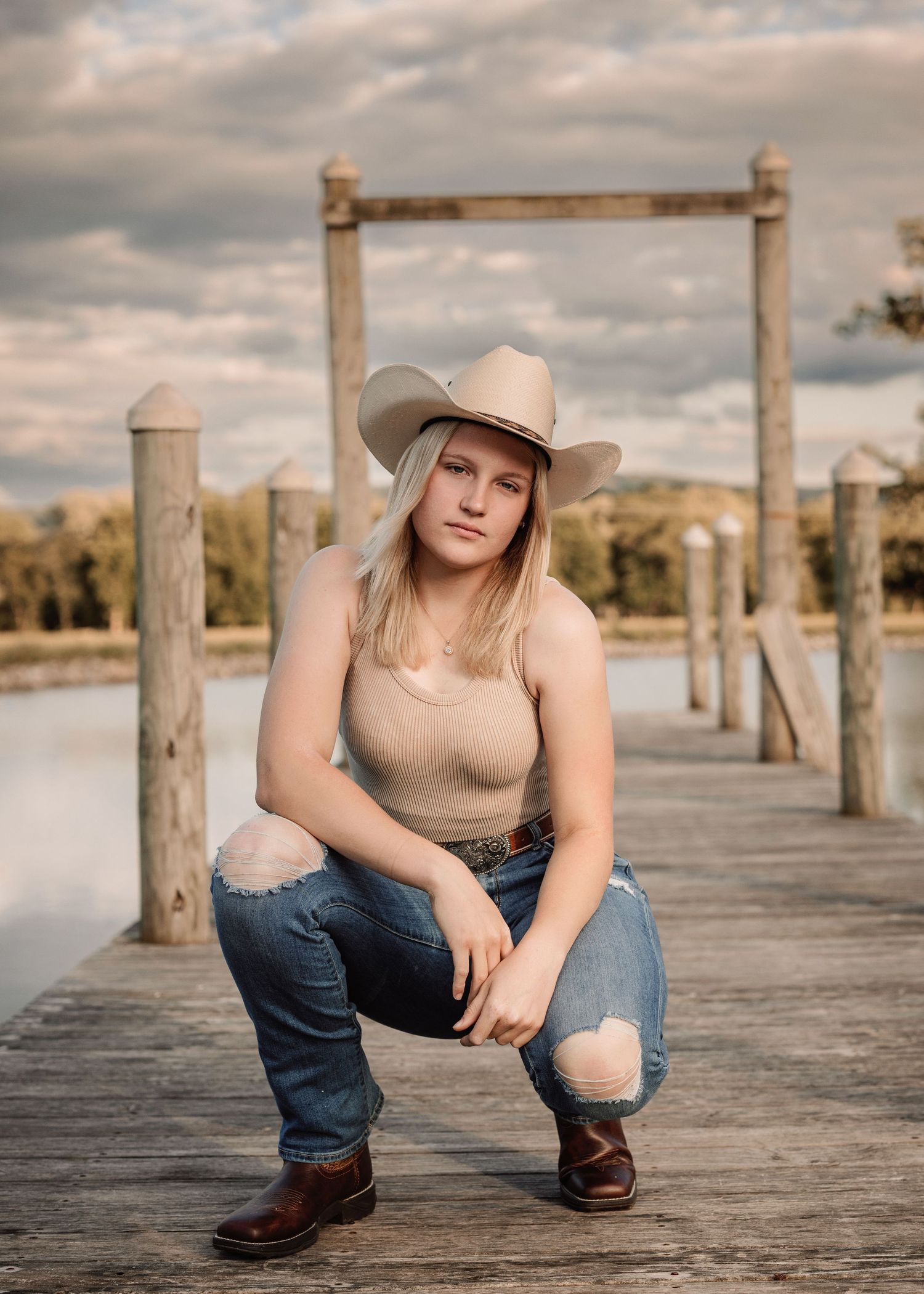 Casual western style portraits on wooden dock with cowboy hat and boots.