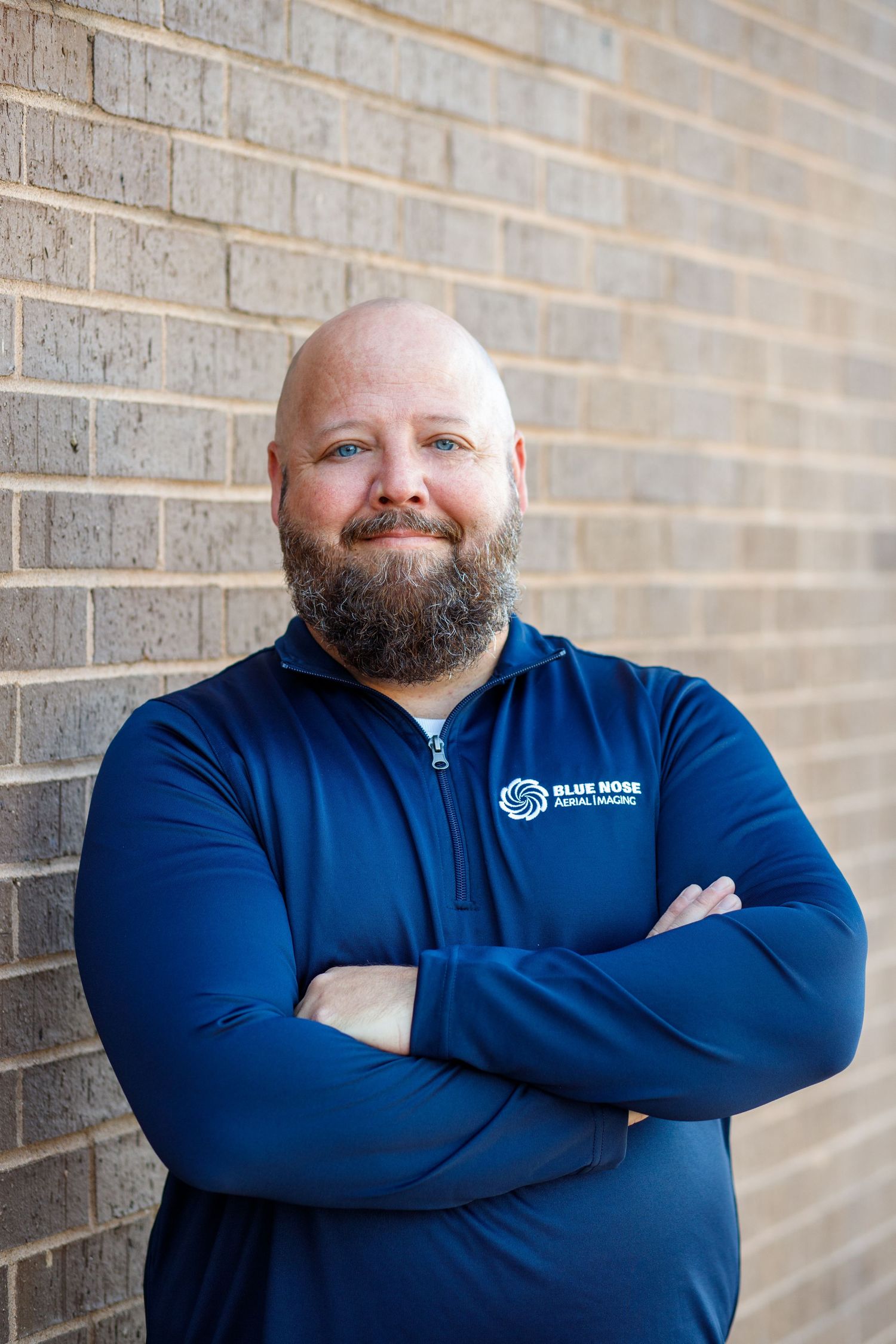 A person in a navy shirt and khaki pants sits casually on a wooden bench outside a storefront.