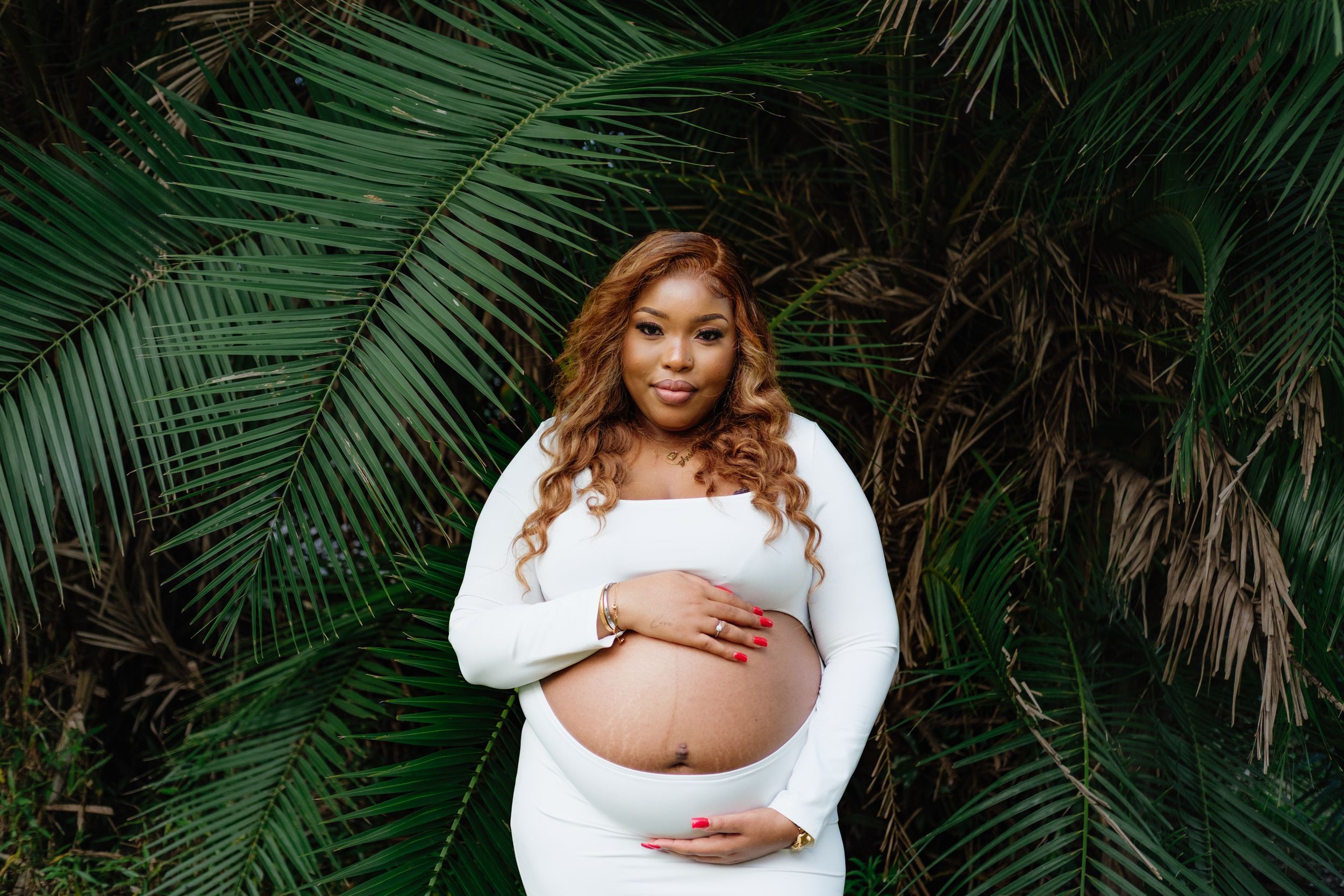 Maternity portrait with soft palm fronds creating a natural botanical backdrop