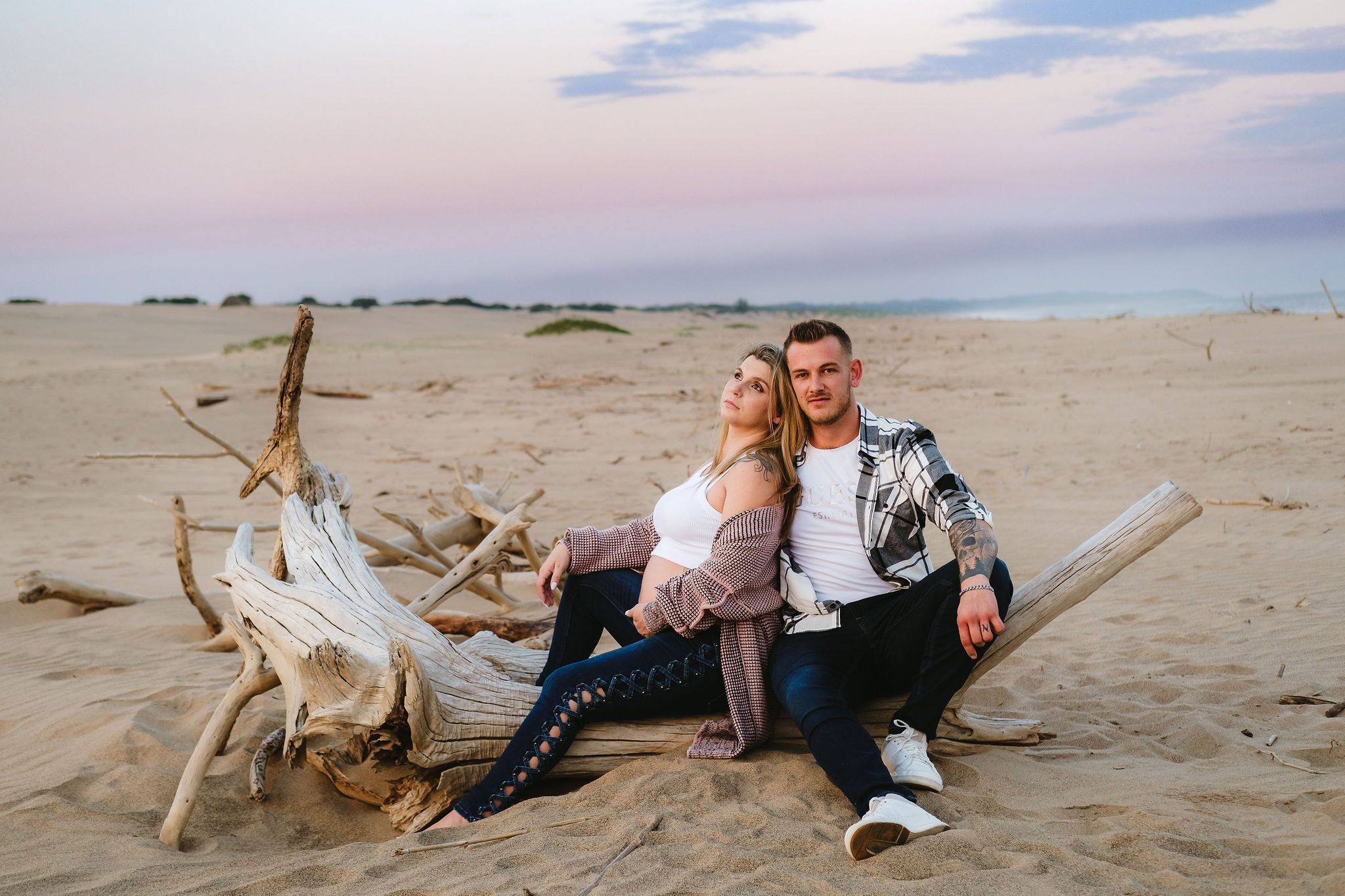 Maternity couple sitting on a washed-up log at Mtunzini Beach