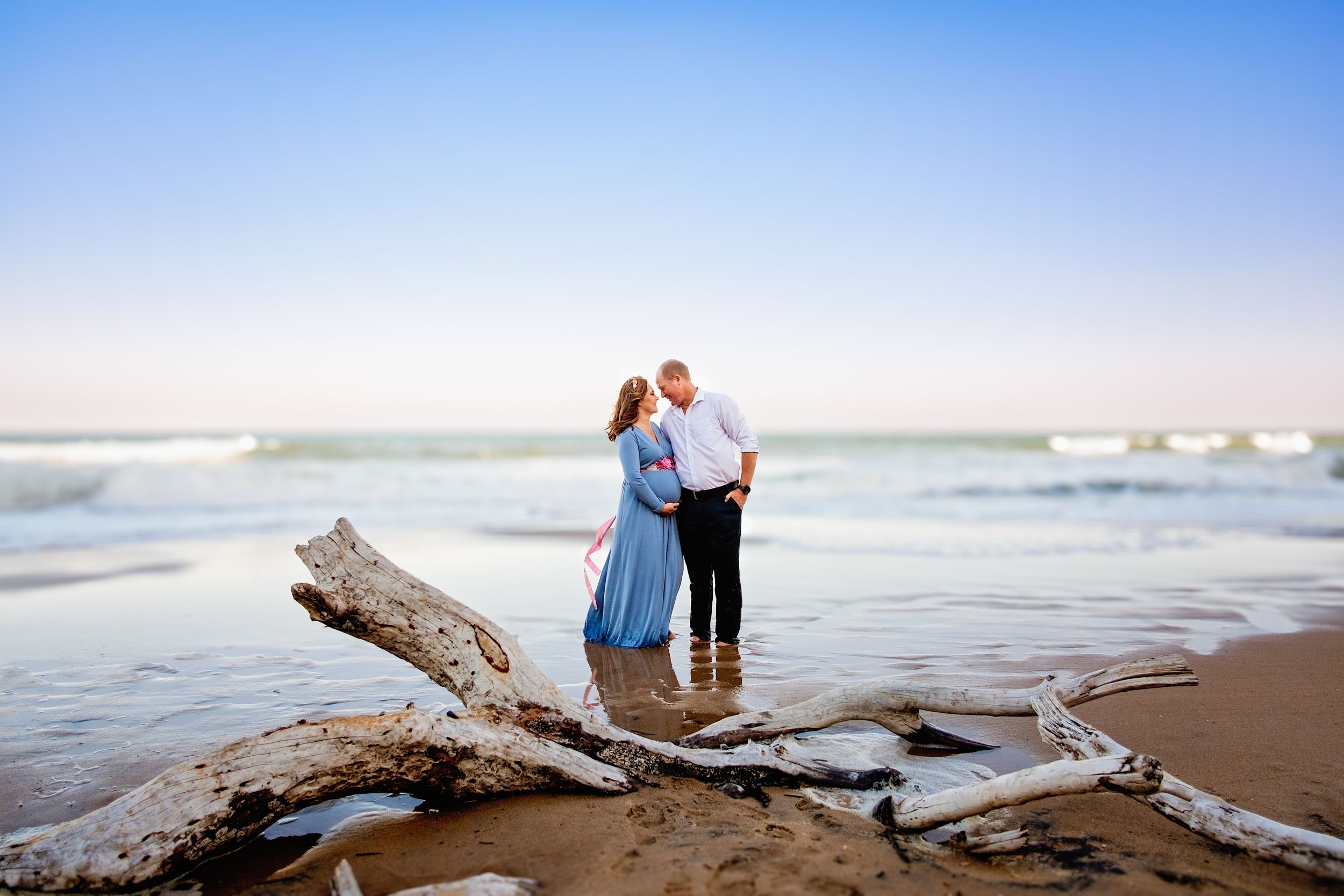 Maternity couple photographed with the sea as a soft natural backdrop