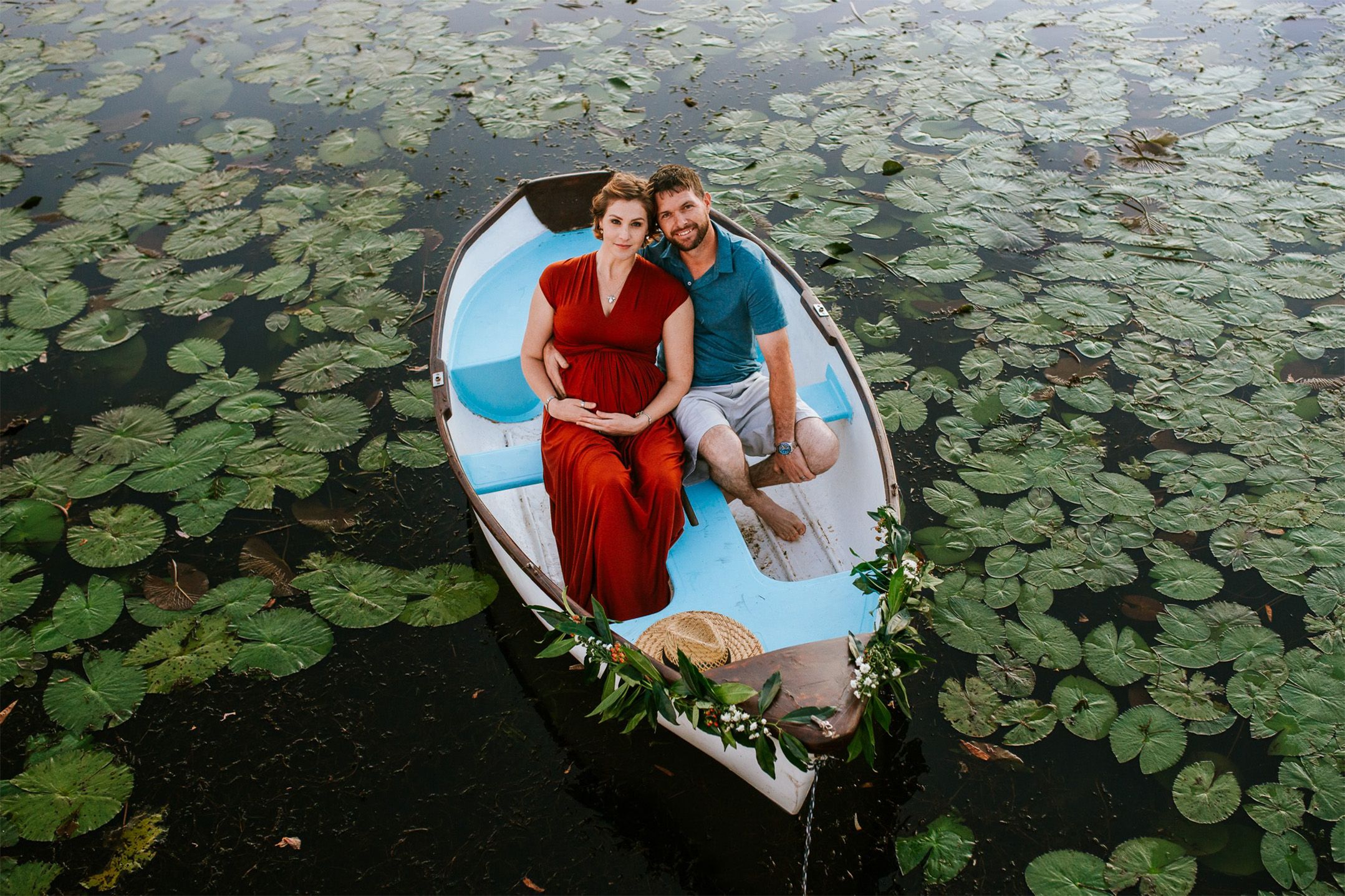 Maternity couple photographed on a boat surrounded by lily pads