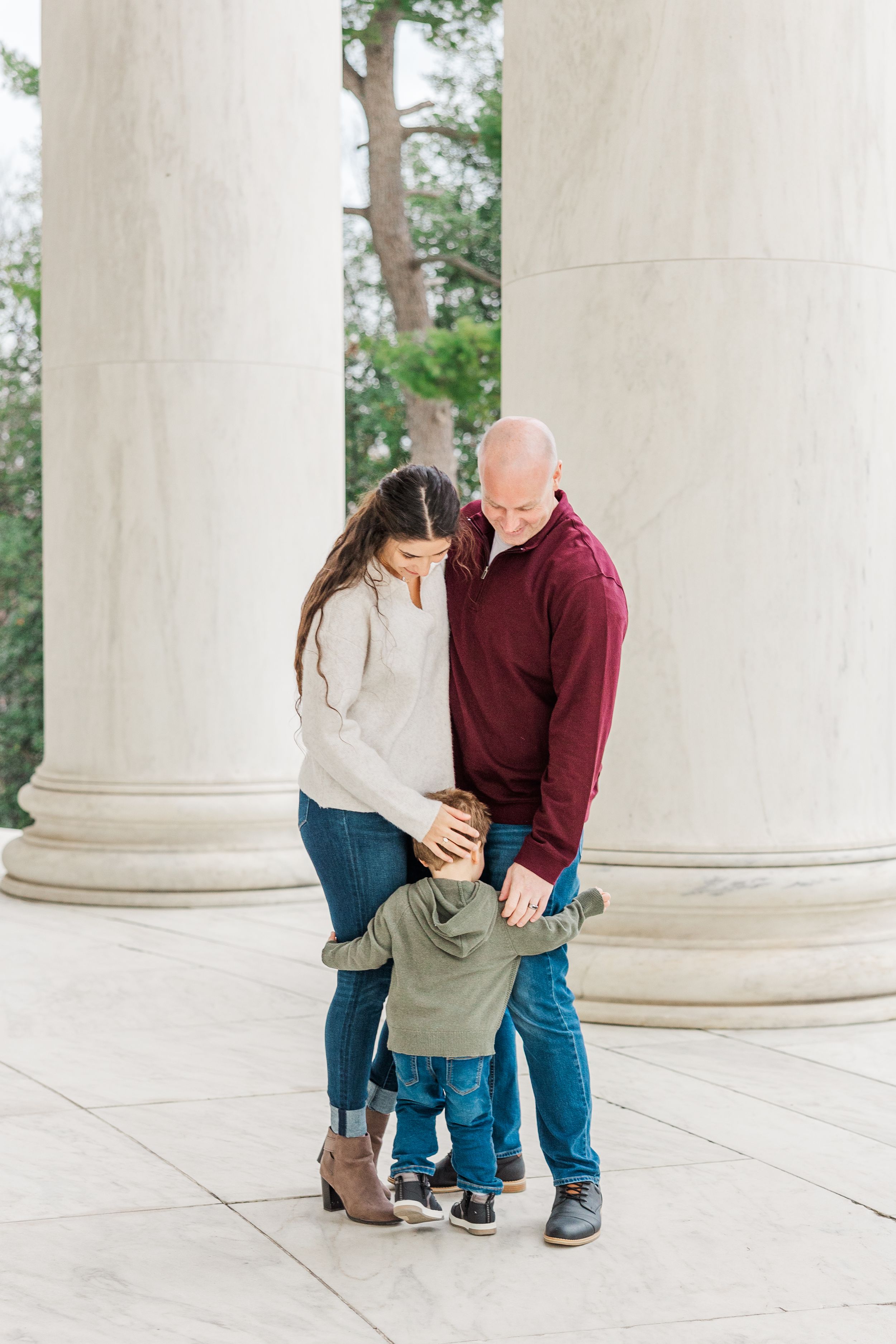 Family photoshoot between white columns showing intimate moments and interactions.