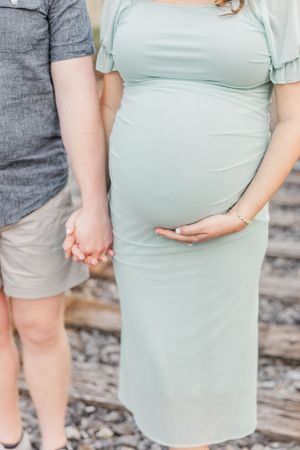 Side view of pregnant woman in mint green dress showing baby bump.