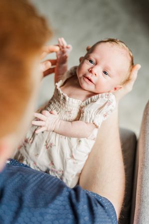 Close-up portraits of newborn baby in cream-colored outfit against neutral background.