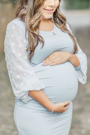 Close-up of a pregnant woman wearing a blue dress with white dotted sleeves.