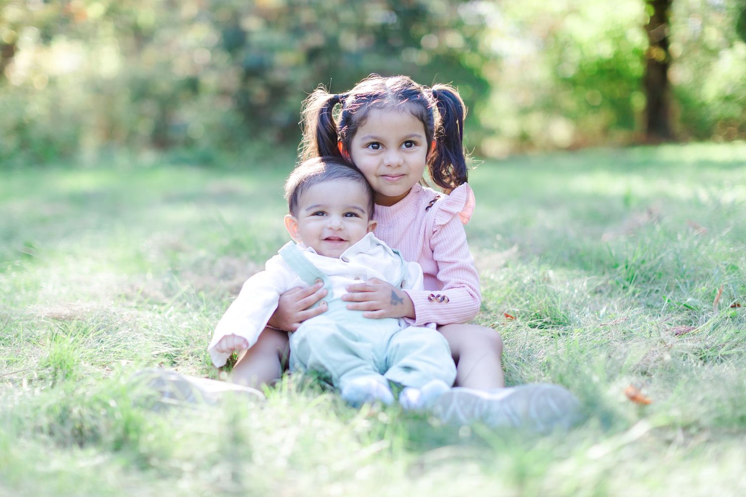 Two children in plaid and polka dot shirts sit and play together in a garden filled with yellow wildflowers for Tree Farm Mini Sessions