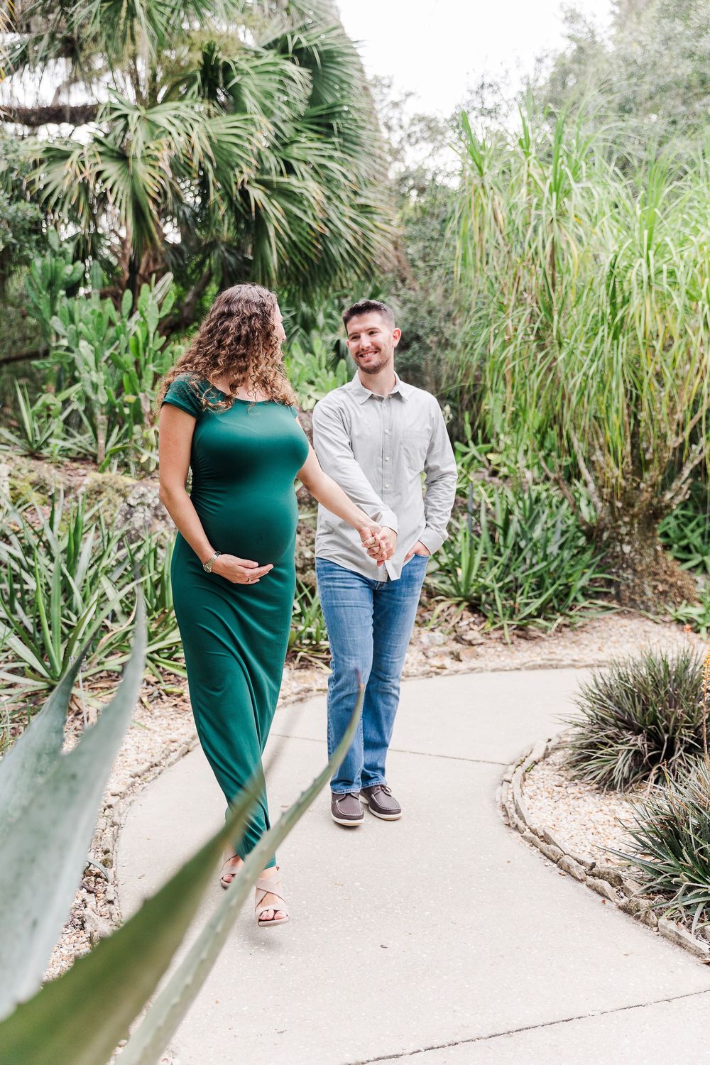 Couple walking together on a garden path surrounded by tropical plants and palm trees.