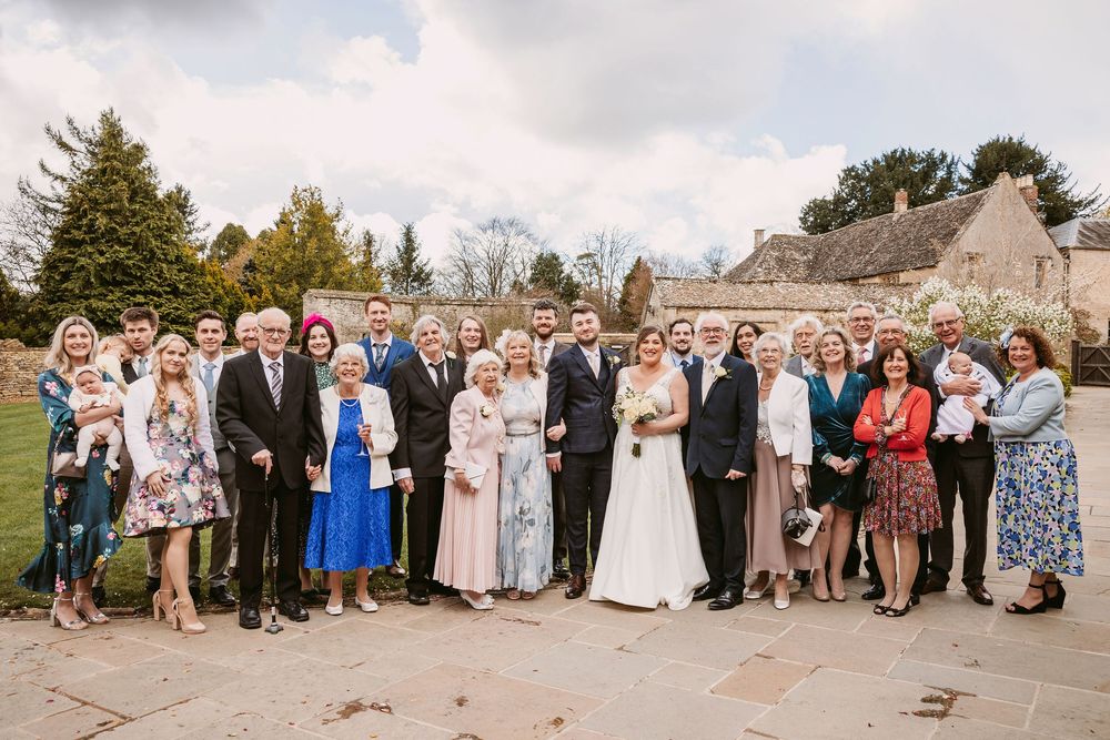 Wedding party and guests gather outdoors for a series of group photos at a scenic venue.