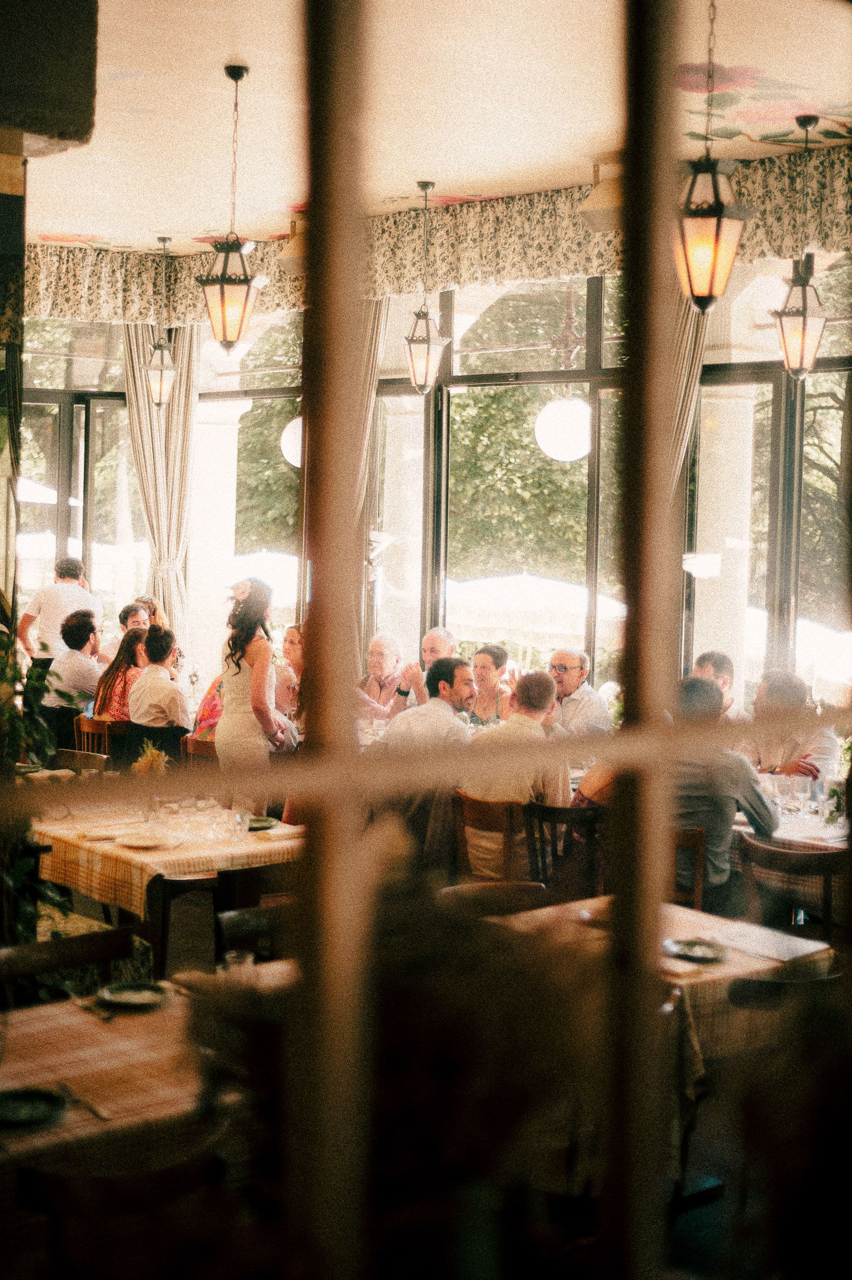 Panoramic view of a dimly lit restaurant interior with soft lighting and diners seated at tables near large windows.