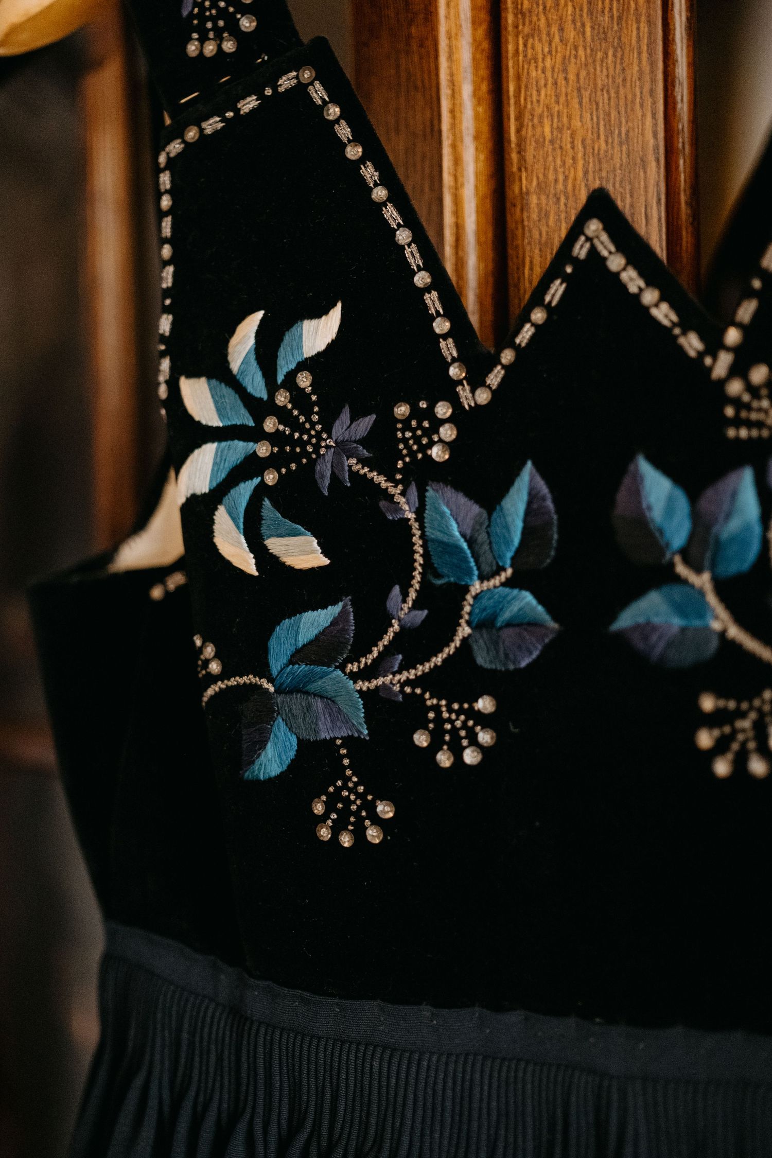 Black fabric with embroidered blue floral design and beaded embellishments.