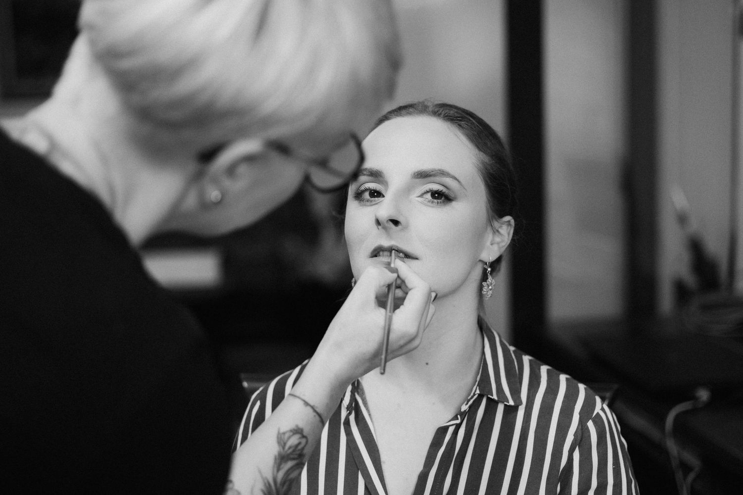 Person getting makeup professionally applied with brushes and beauty products.