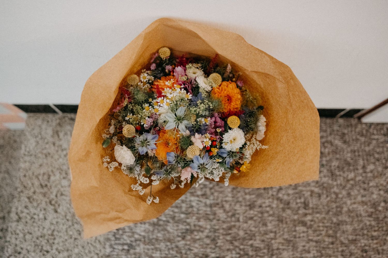 Colorful dried flower bouquet wrapped in brown kraft paper.