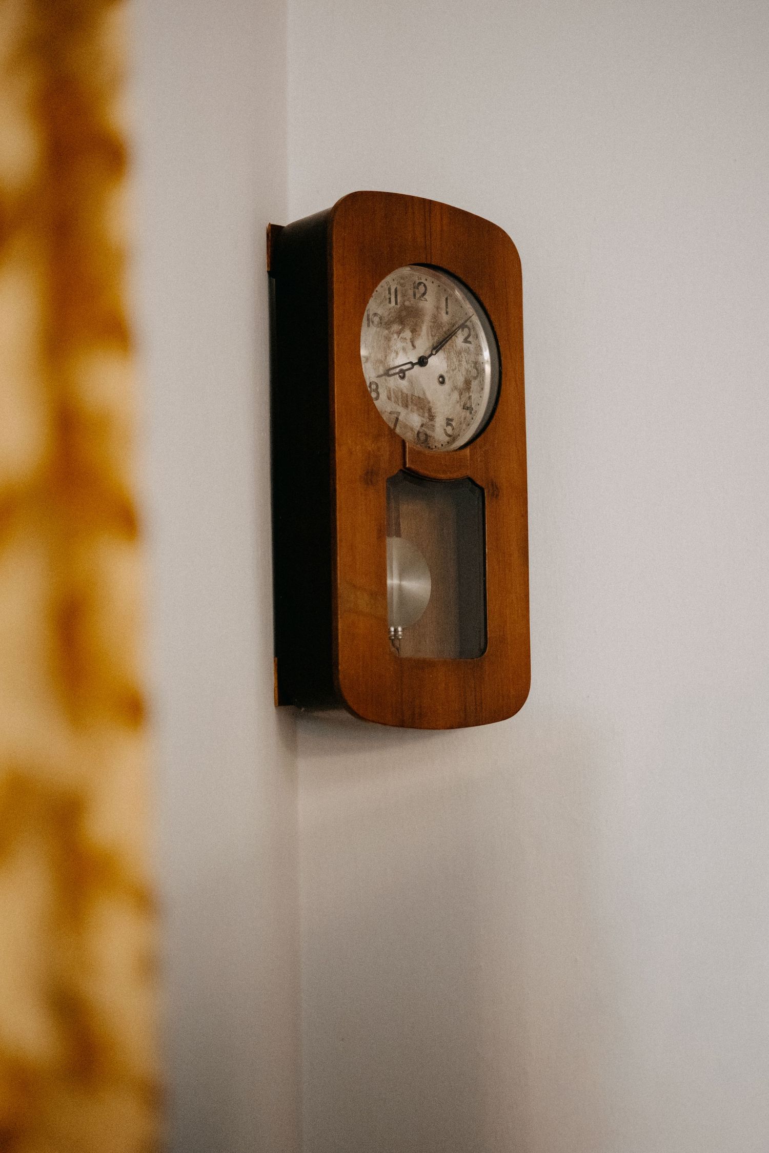 A vintage wooden wall clock mounted on a white wall.