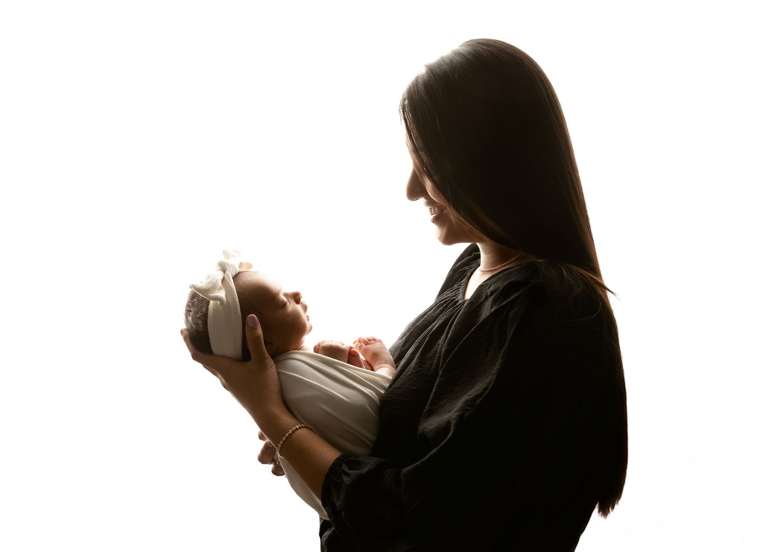 New Hampshire newborn photography silhouette of a mother holding her baby, minimalist studio portrait celebrating motherhood.