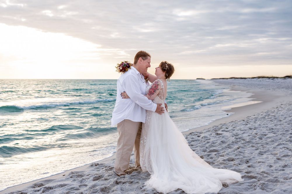 A romantic beach wedding photoshoot at sunset with waves crashing on the shore and soft golden light.