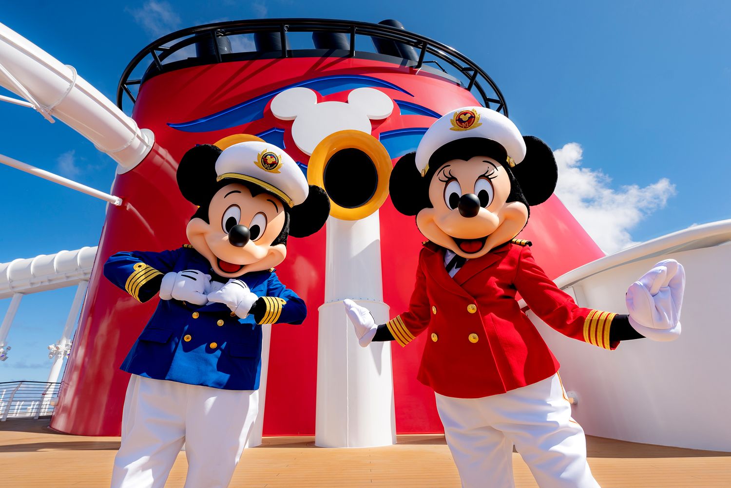 Colorful cruise ship deck with red and white decor features Disney character figures in sailor outfits against a blue sky.