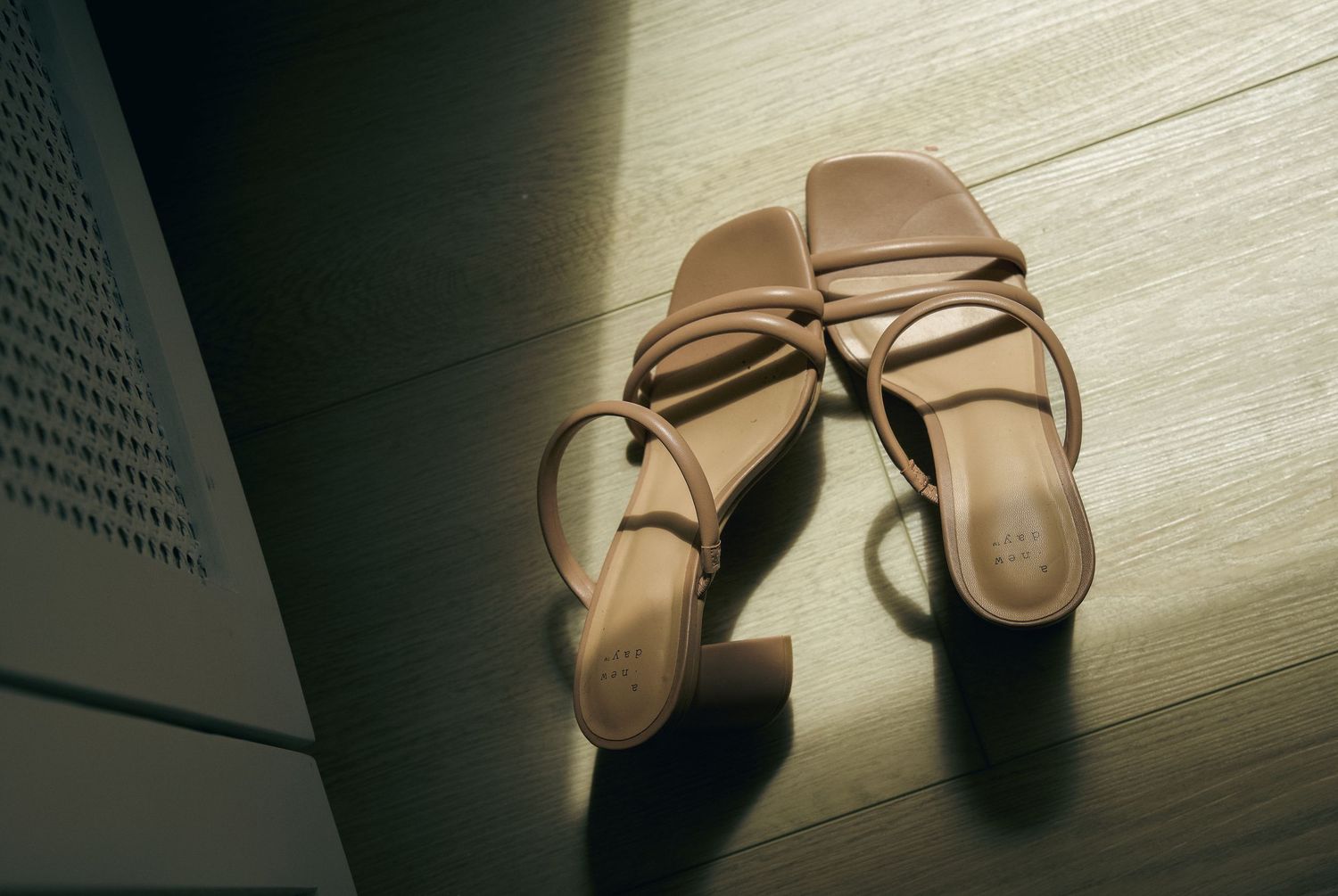 A pair of beige ballet flats shown in different positions against a white textured background.