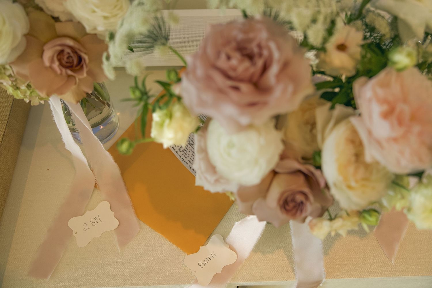 Delicate dusty pink and cream roses arranged in an elegant floral centerpiece with greenery accents.