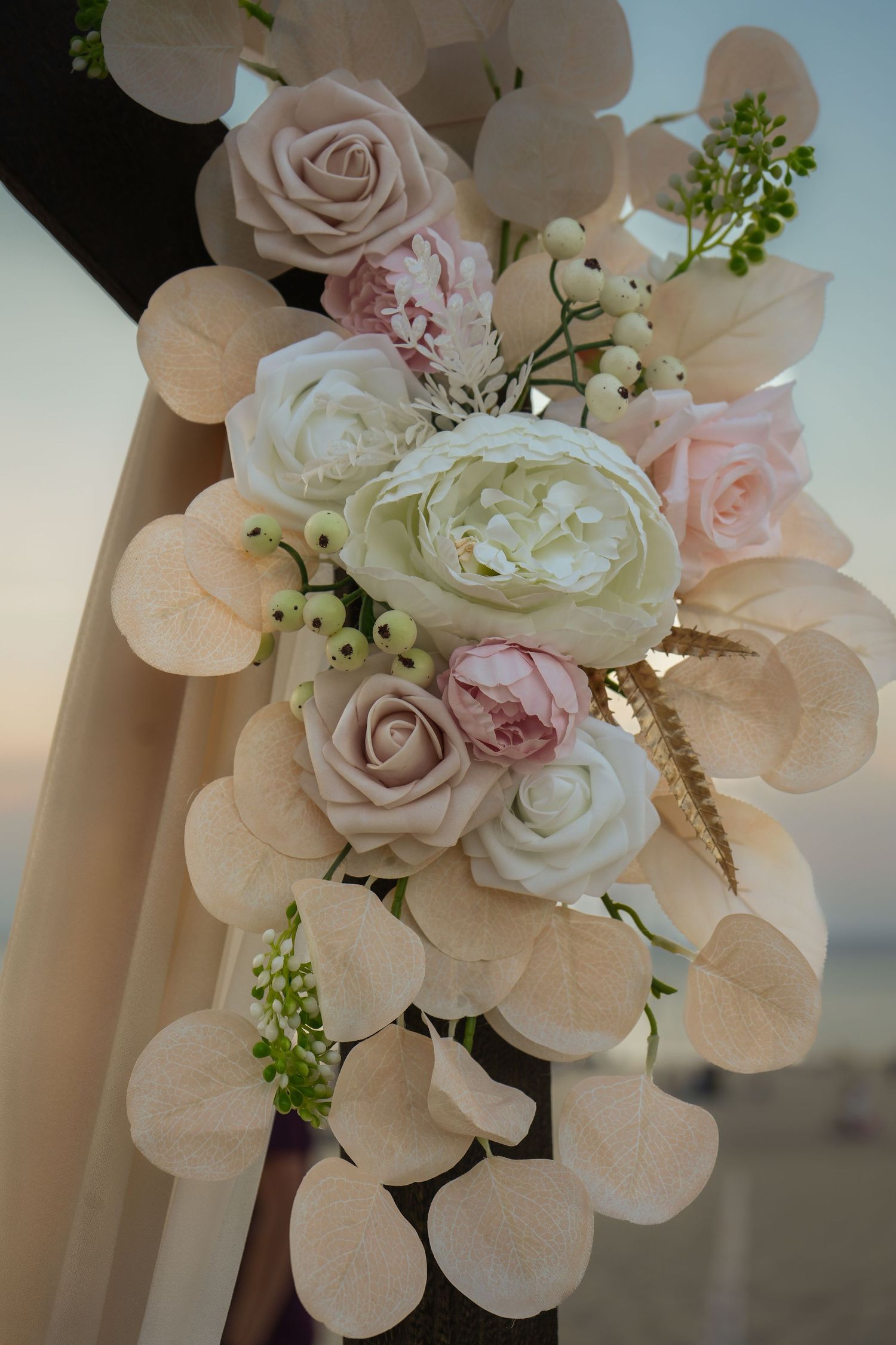 Close-up of elegant blush pink and white roses with delicate green foliage arranged in a romantic wedding bouquet.