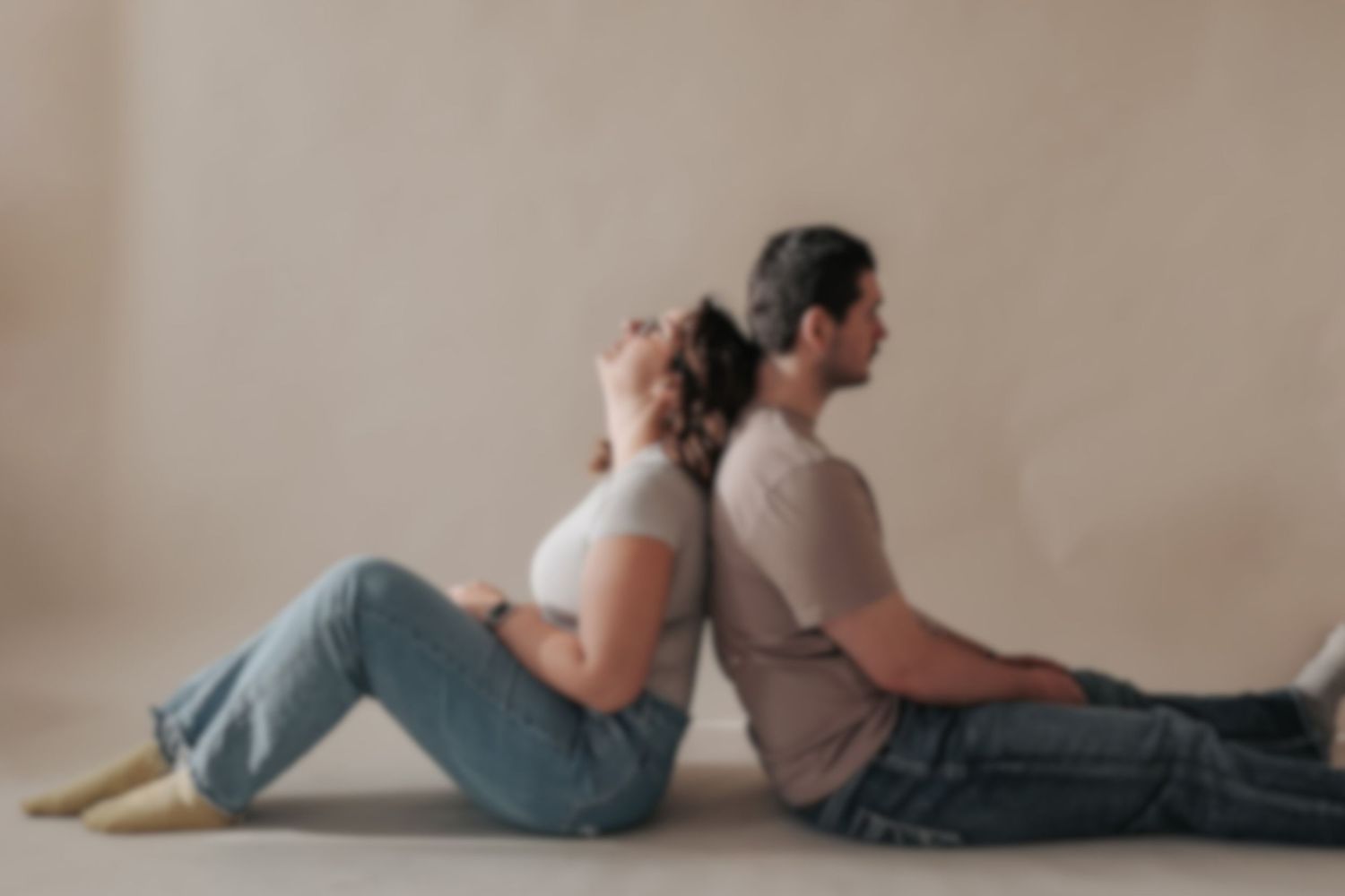 Two people lying on a beige floor in casual clothing during a lifestyle photoshoot.